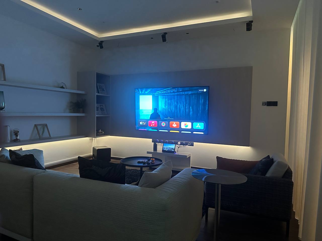 A living room with a large television, a white couch, and a coffee table.
